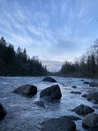 Scenic view of rocks by river against sky