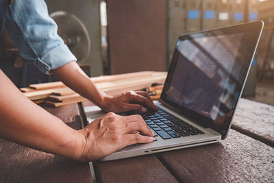 Midsection of man using laptop on table