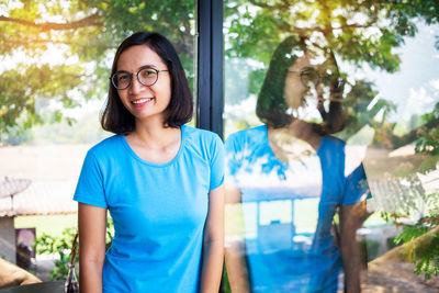 Portrait of smiling woman reflecting on window