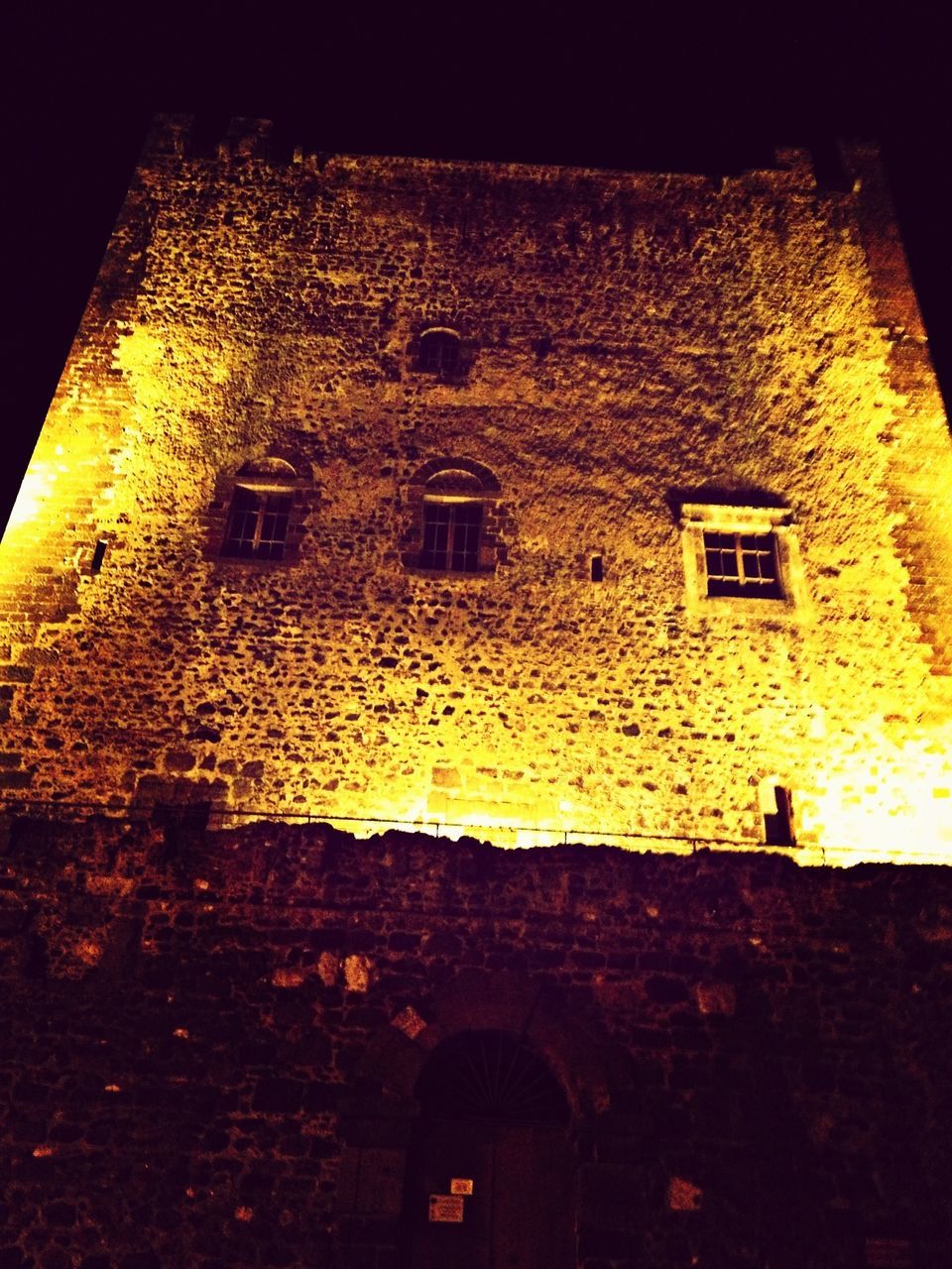 architecture, built structure, building exterior, night, window, illuminated, building, yellow, low angle view, residential building, arch, residential structure, house, brick wall, old, dark, wall - building feature, no people, outdoors, street