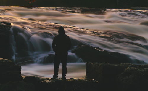 Rear view of man standing on rock against sea