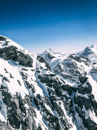 Scenic view of snow covered mountains against blue sky