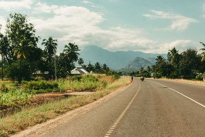 Road by trees against sky