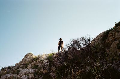 Low angle view of man on rock against sky