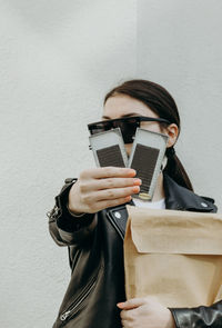 A girl with a shopping bag holds out a package of eyelash extensions.