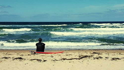 Rear view of man sitting on beach