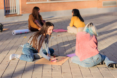 Females drawing on poster outdoors