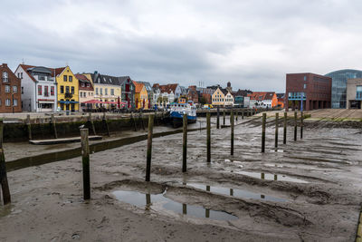 Wooden posts by buildings against sky in city