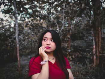 Portrait of beautiful young woman against trees