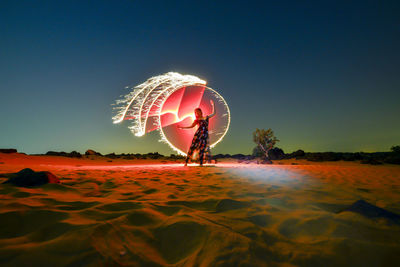 Full length of woman standig on sand against wire wool and sky