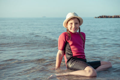 Portrait of smiling woman sitting on beach against sky