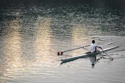 Rear view of man canoeing on river