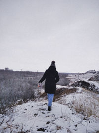 Rear view of man on snowy field against sky