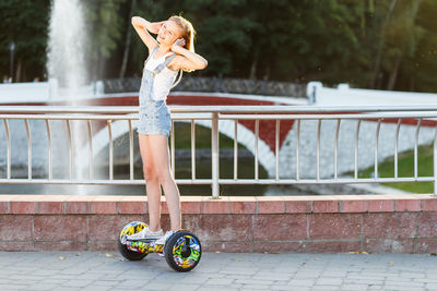 Girl standing on hoverboard against bridge