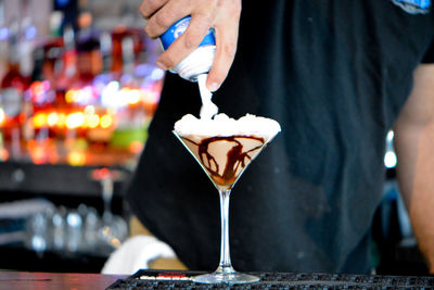 Midsection of man preparing drink on table