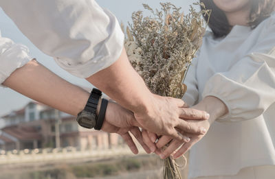 Cropped hands of man giving bouquet to woman