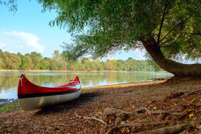 Boat moored on shore by lake against sky