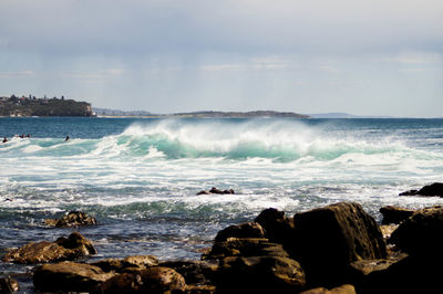 Waves rushing towards shore against sky