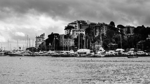 Sailboats moored in sea against buildings in city