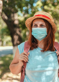 Caucasian tourist girl in summer straw hat with  backpack and  protective mask. travel and vacation