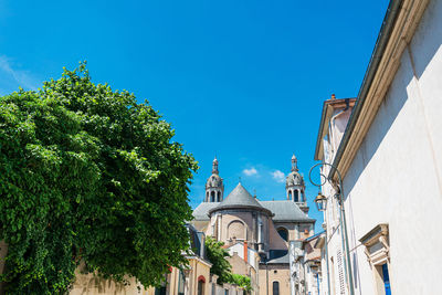 Low angle view of trees and building against blue sky