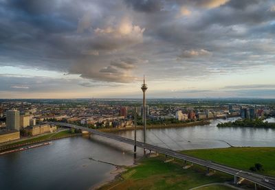 High angle view of bridge over river by buildings against cloudy sky