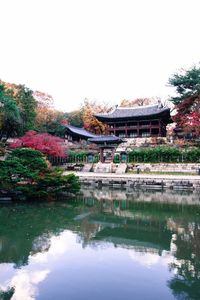 Built structure in front of pond in park against clear sky