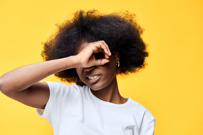 Portrait of young woman against yellow background