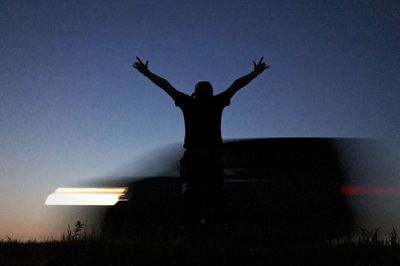 Rear view of silhouette person standing on field against sky at sunset