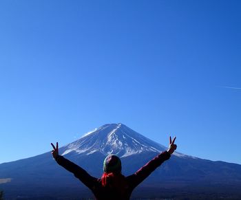 Man with arms raised in winter against clear blue sky
