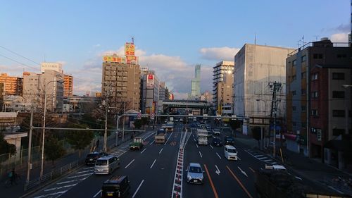 Traffic on city street amidst buildings against sky