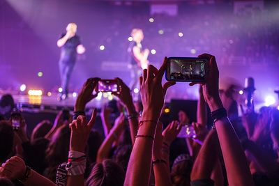 Rear view of people photographing at concert