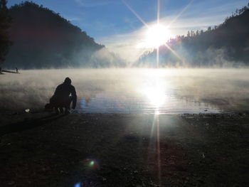 Rear view of man on shore against sky