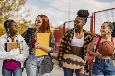 Young woman walking with friends on footpath