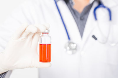 Midsection of doctor holding liquid in container