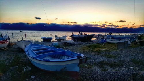 Boats moored in sea at sunset