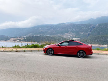 Side view of red car on road against sky