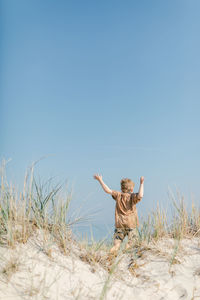 Boy running on sand dune