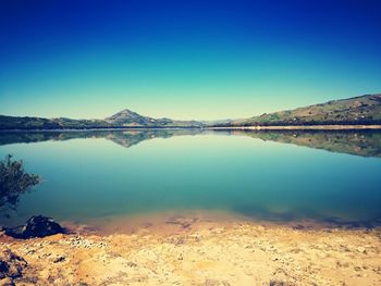 Scenic view of lake against clear blue sky