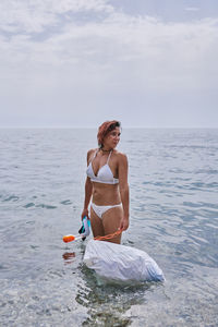 A young girl with diving goggles pulling trash out of the ocean. recycling concept