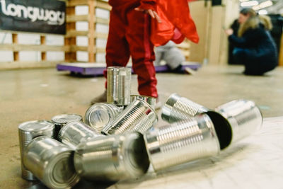 Midsection of child standing by metallic containers on floor