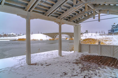 Snow covered land by sea against sky