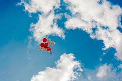 Low angle view of balloons flying against blue sky