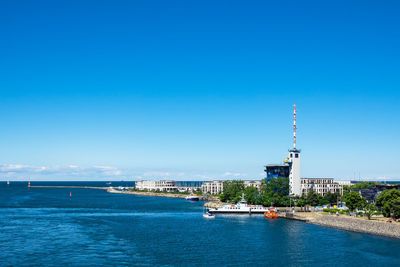 Buildings by sea against blue sky