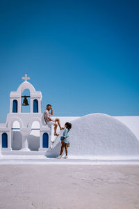 Couple on land against clear blue sky