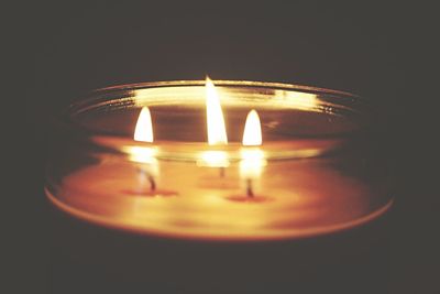 Close-up of lit candle in dark room