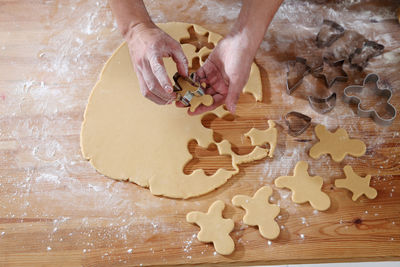 Cropped hands of chef cutting dough with pastry cutter at table