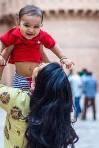 Cute toddler baby boy smiling at mother hand and touch in casual appearance at outdoor