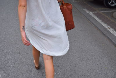 Low section of woman walking on city street