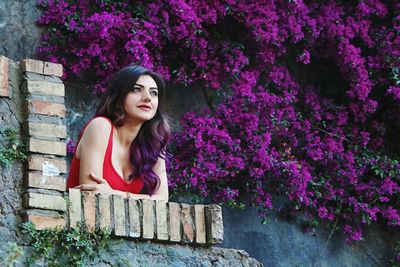 Beautiful young woman with violet ombre hair in front of matching flowers